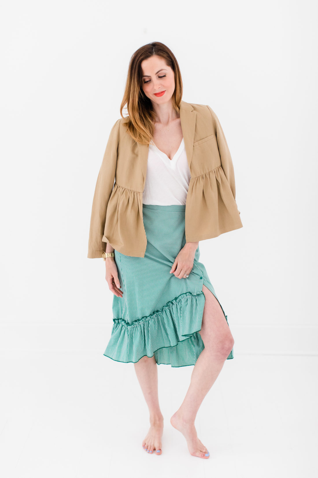 Eva Amurri Martino wears a green gingham ruffled skirt, white Tee, and tan ruffled jacket by BURU as part of a post about how to pack a suitcase