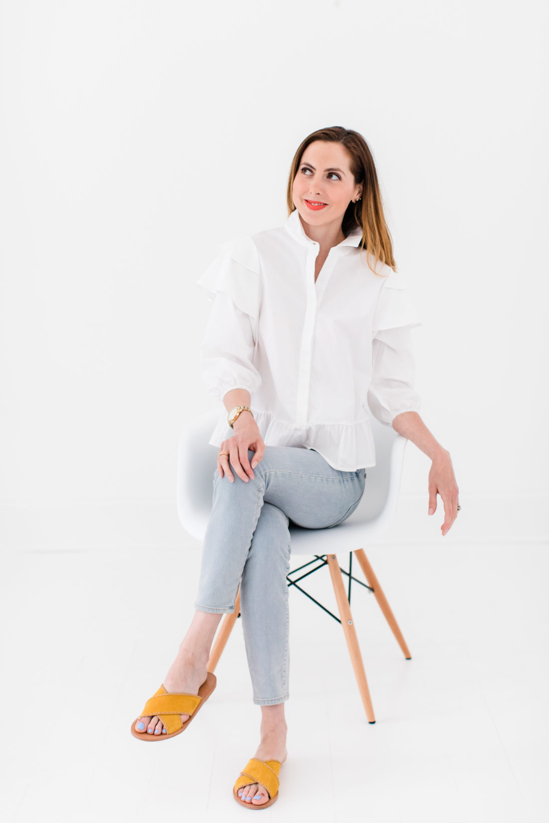 Eva Amurri Martino wears a white button down shirt with ruffle details and jeans with flats