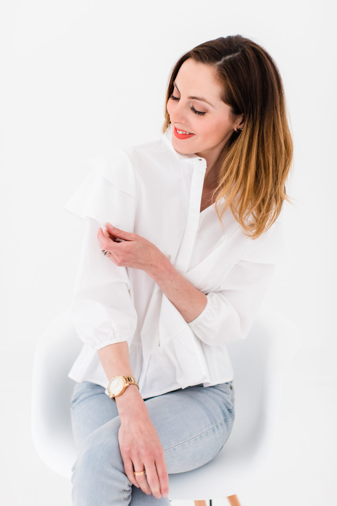 Eva Amurri Martino wears a white button down shirt with ruffle details and jeans with flats
