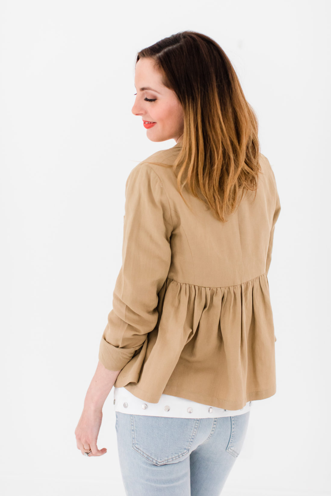 Eva Amurri Martino wears a white bow top, camel ruffle jacket, and jeans as part of a post about packing simply