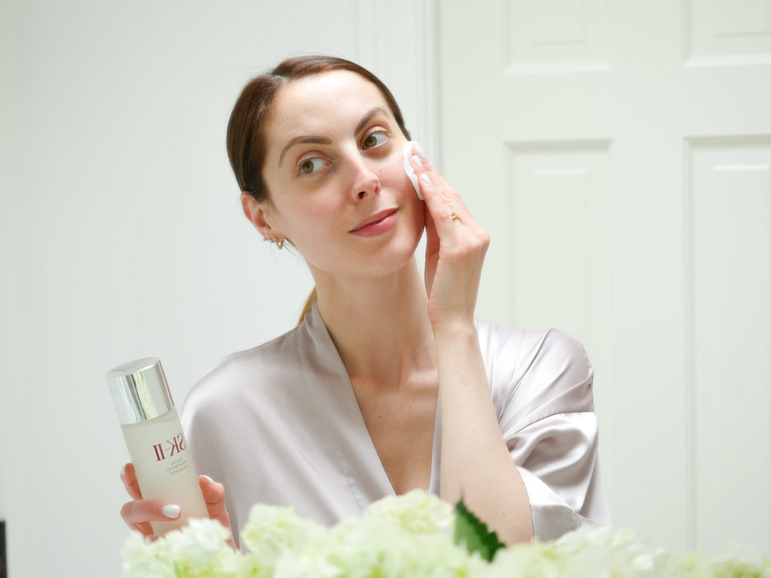 Eva Amurri Martino wears a lilac silk robe and applies SKII facial treatment essence with a cotton pad