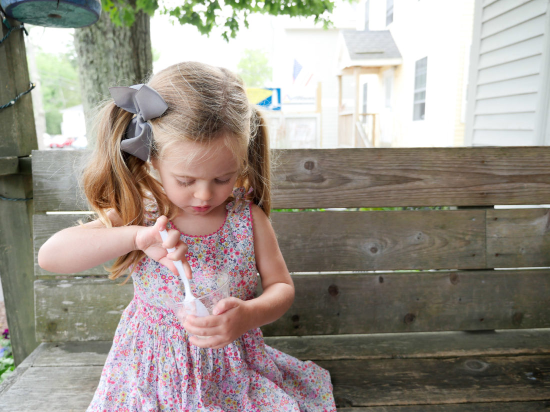 Marlowe Martino eats a cup of fresh strawberry ice cream, wearing a flowered summer dress
