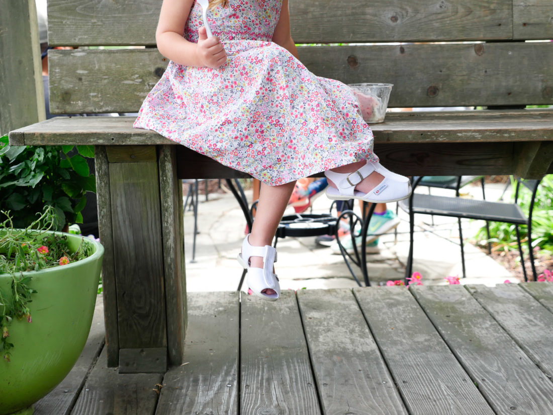 Marlowe Martino eats a cup of fresh strawberry ice cream, wearing a flowered summer dress