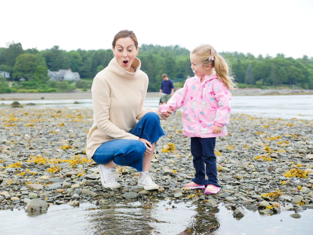 Eva Amurri Martino laughs and looks on as daughter Marlowe plays in the tidal pools on the beach in Maine