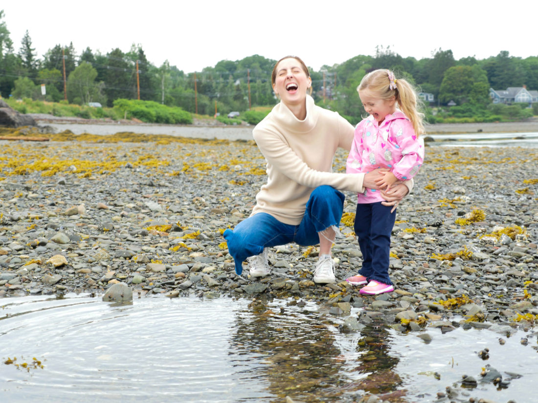 Eva Amurri Martino laughs and looks on as daughter Marlowe plays in the tidal pools on the beach in Maine