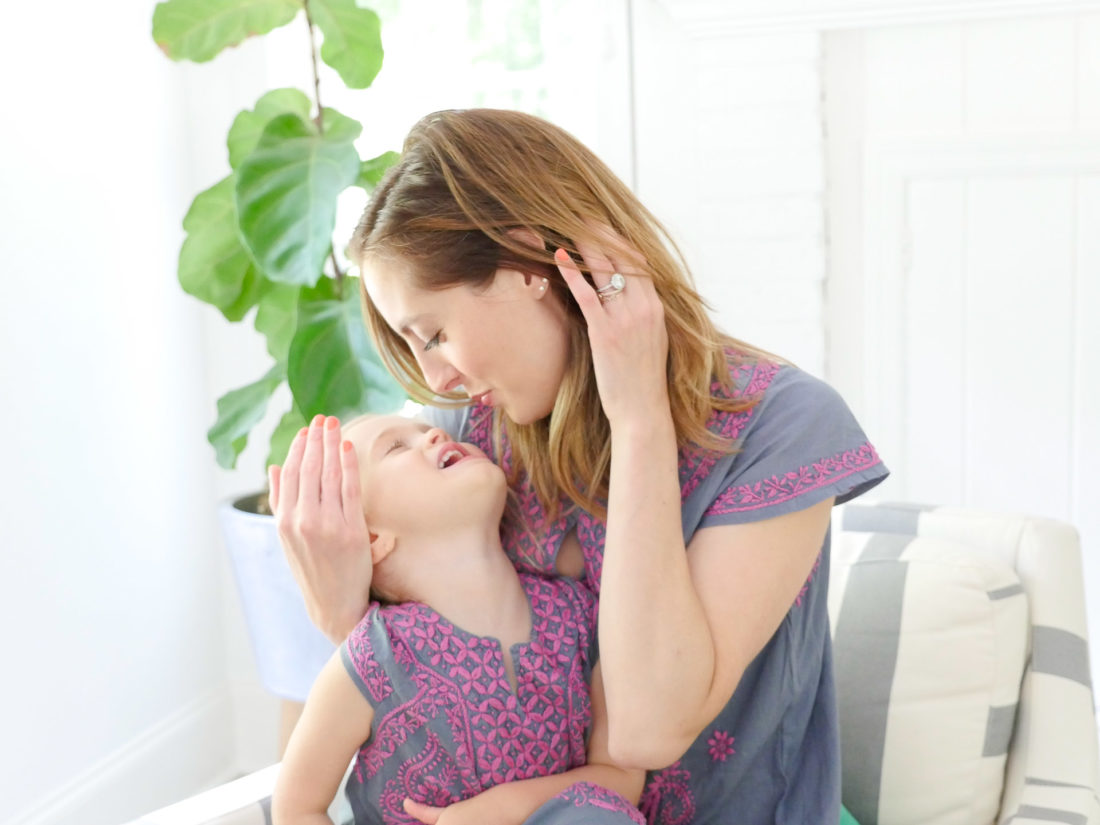 Eva Amurri Martino and Marlowe Martino wear matching embroidered dresses and sit together in a striped armchair in the family room of their Connecticut home