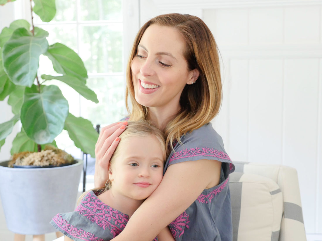 Eva Amurri Martino and Marlowe Martino wear matching embroidered dresses and sit together in a striped armchair in the family room of their Connecticut home