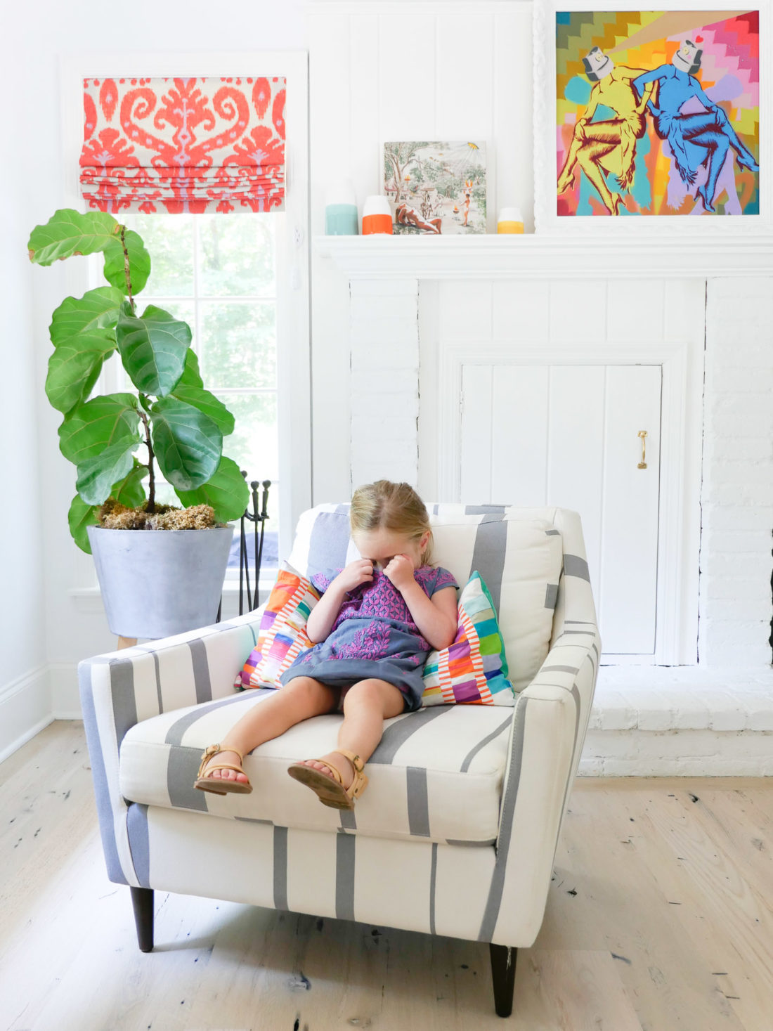 Marlowe Martino wears an embroidered dress and sits in a striped armchair in the family room of her Connecticut home