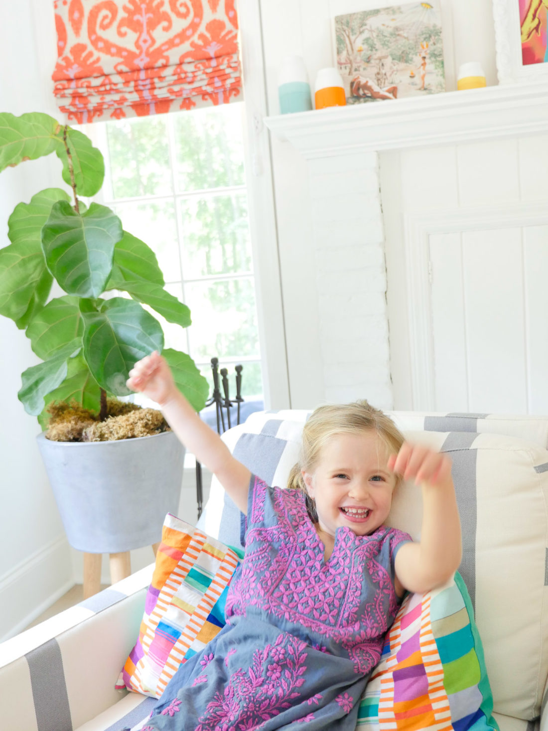 Marlowe Martino wears an embroidered dress and sits in a striped armchair in the family room of her Connecticut home