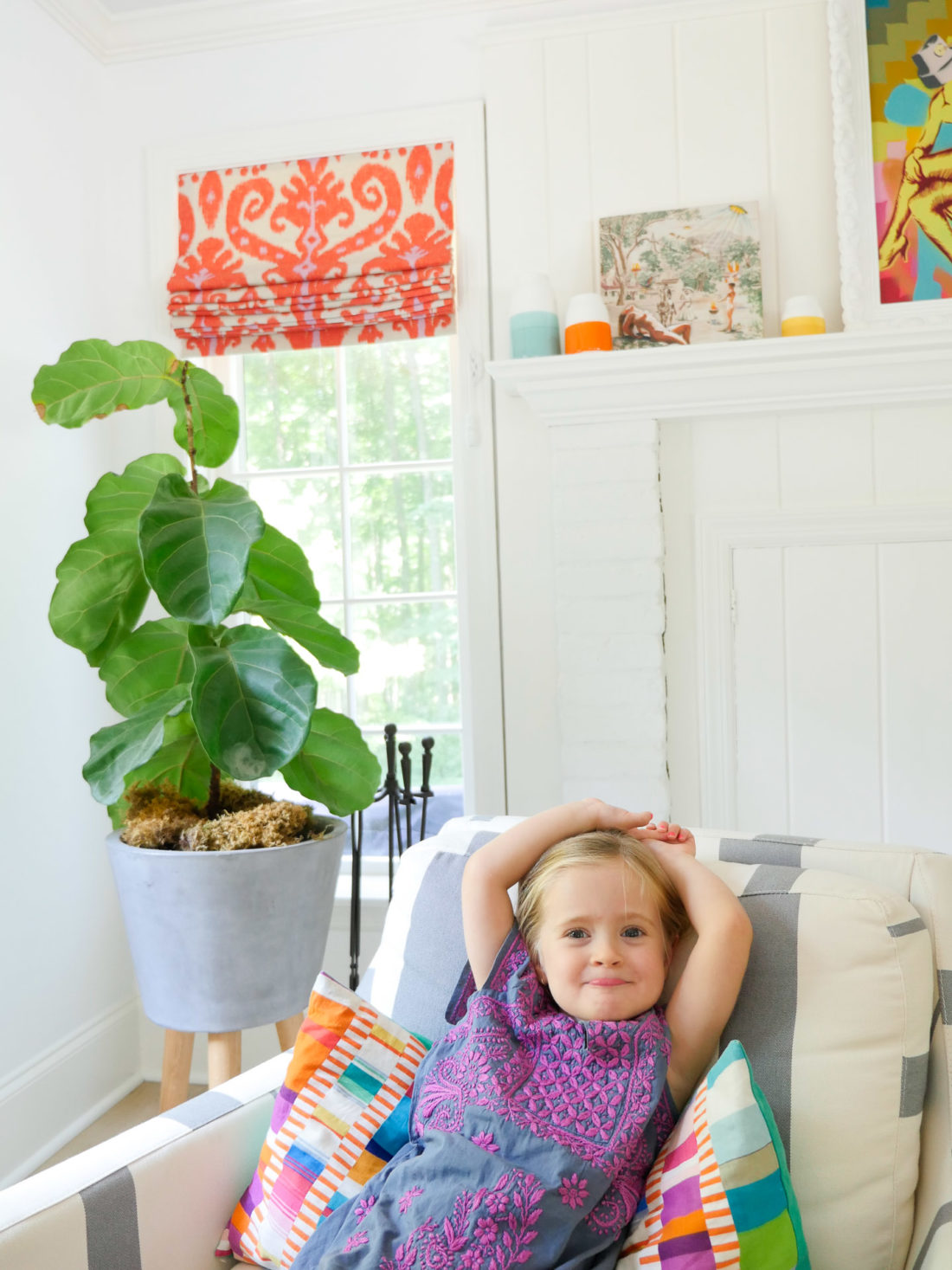 Marlowe Martino wears an embroidered dress and sits in a striped armchair in the family room of her Connecticut home