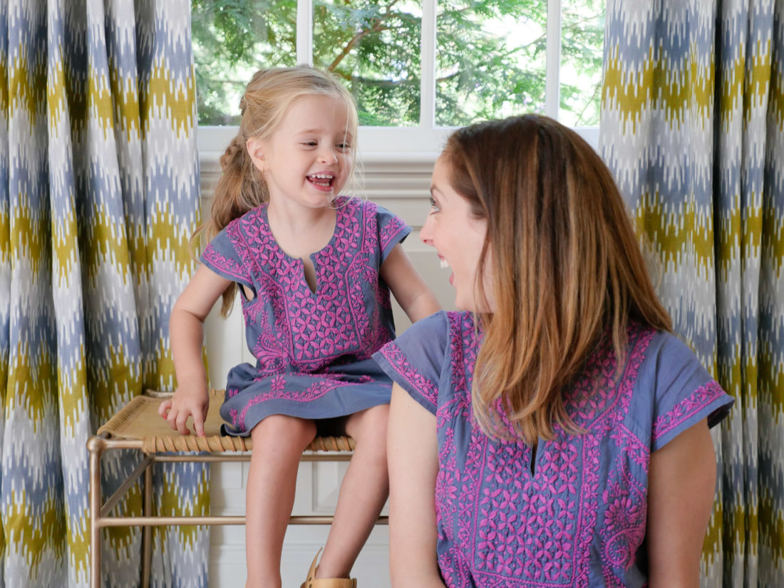 Eva Amurri Martino and Marlowe Martino wear matching embroidered dresses and sit together in the living room of their Connecticut home