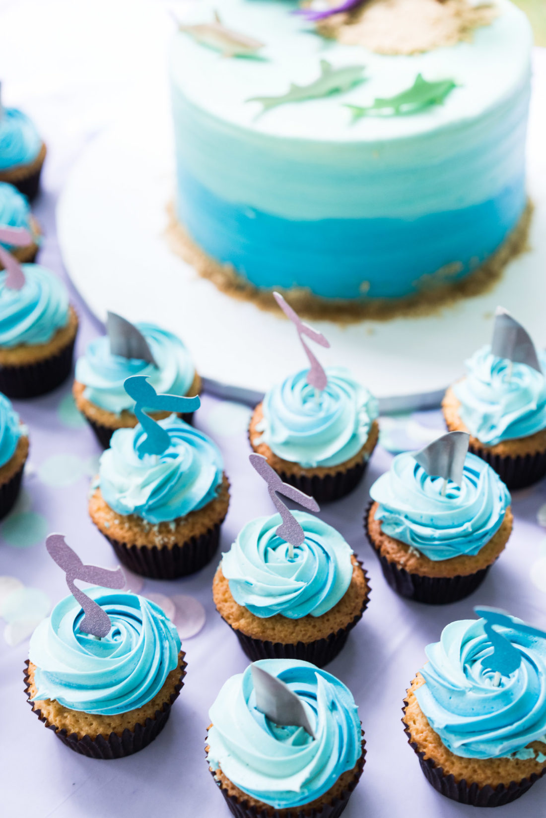 Marlowe Martino's Mermaid and Shark themed birthday cake sits on a table surrounded by cupcakes