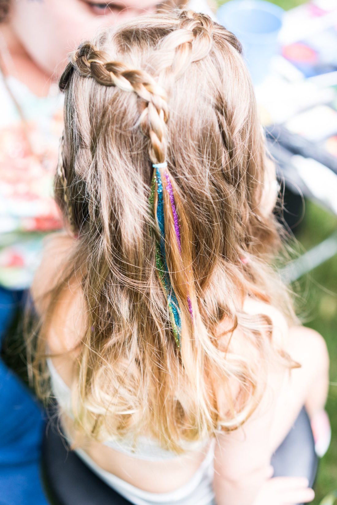 Marlowe Martino gets glitter painted in her hair at the mermaid braid bar at her third birthday party