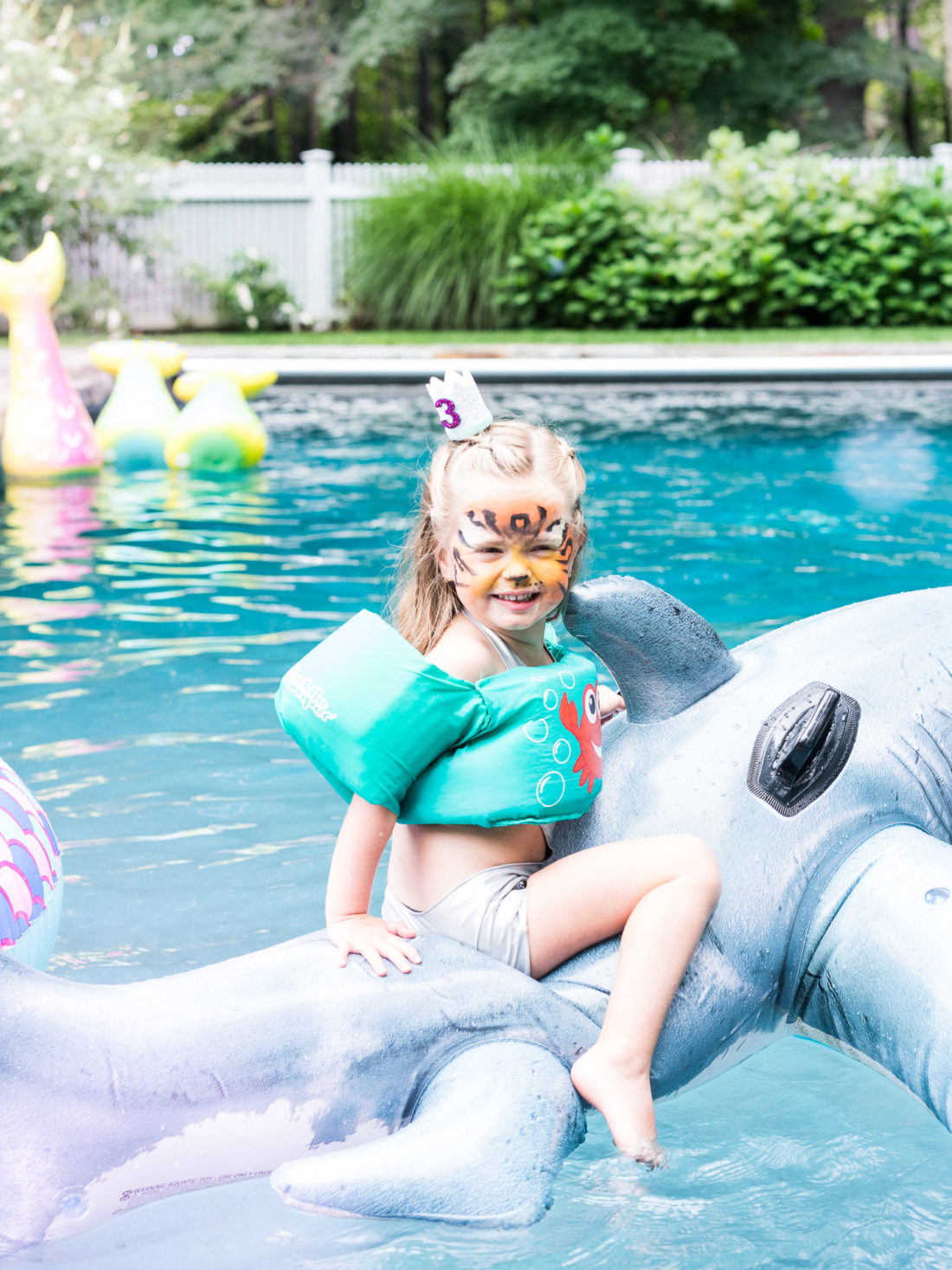 Marlowe Martino rides on a shark pool float in the pool of her Connecticut home at her third birthday party