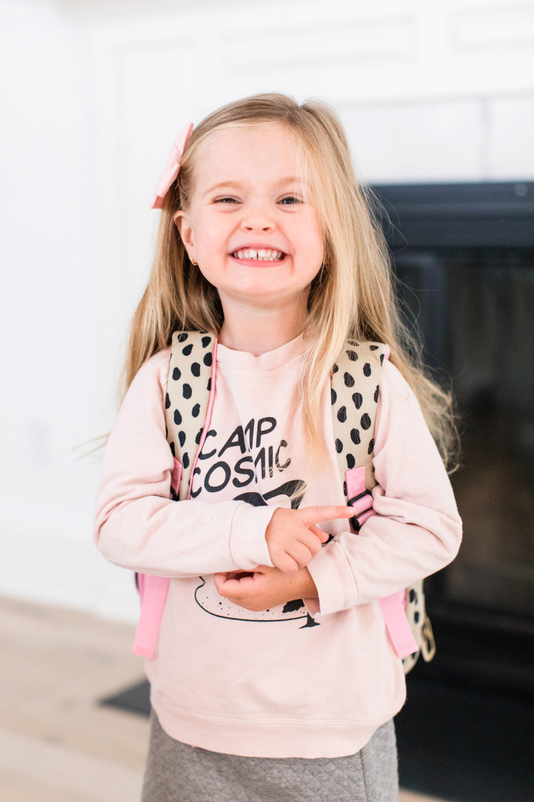 Marlowe Martino wears a pink sweatshirt and smiles as she gets ready for her first day of school