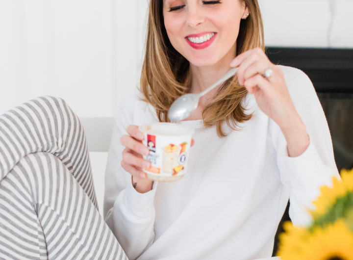 Eva Amurri Martino sits at the kitchen table in a pair of grey and white striped pajamas and eat breakfast next to a vase of sunflowers