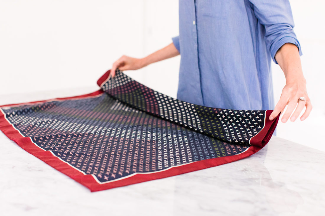 Eva Amurri Martino folds a printed silk scarf to tie around the strap of her purse