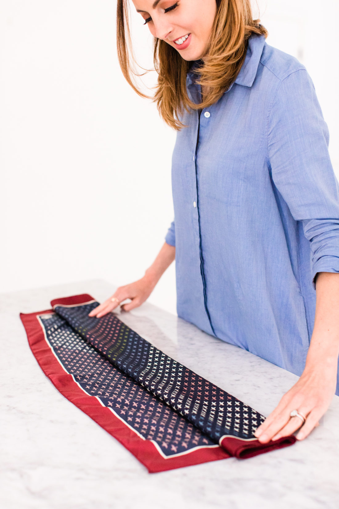 Eva Amurri Martino folds a printed silk scarf to tie around the strap of her purse