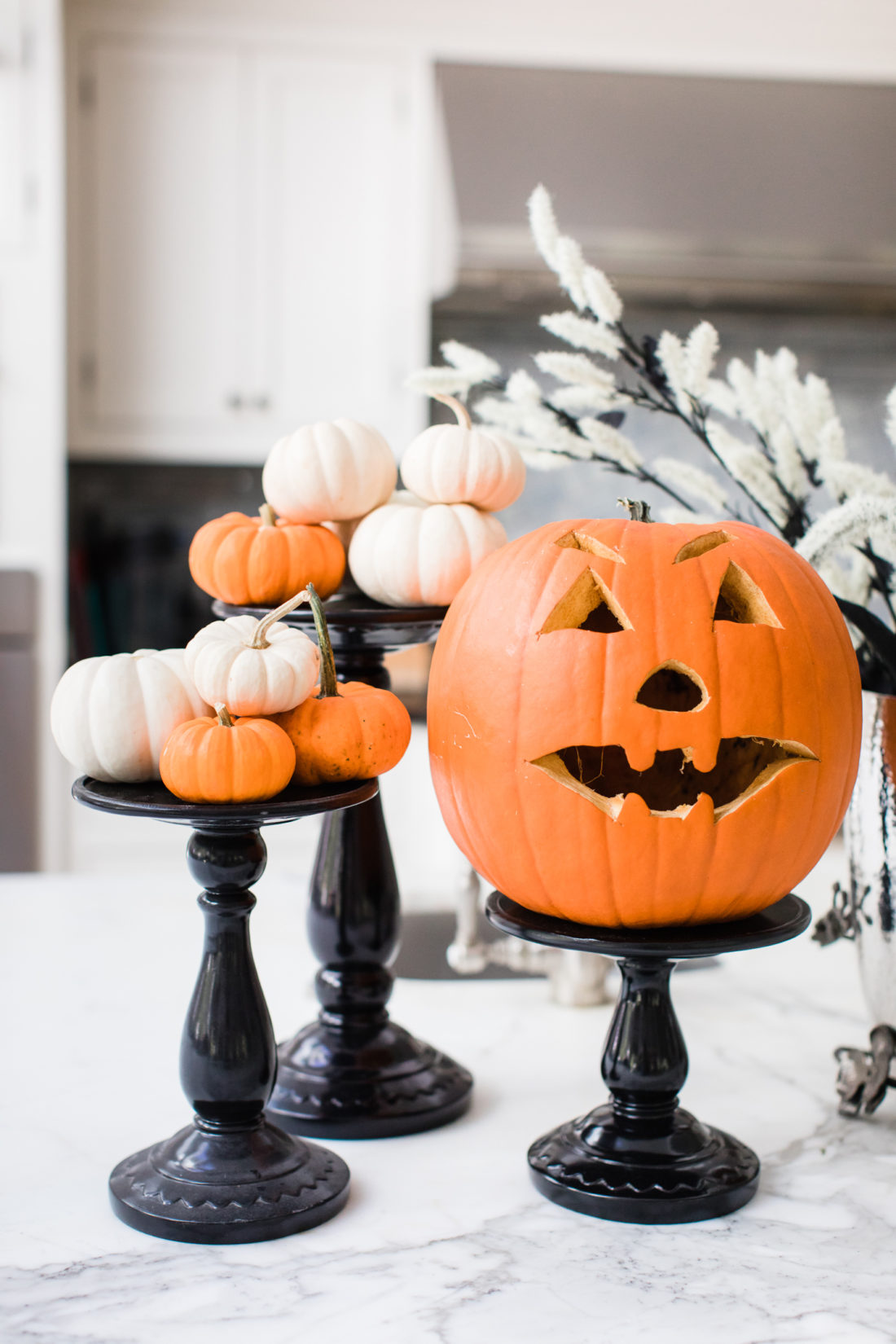 An assortment of Pumpkins on black lacquere stands decorate the marble island in Eva Amurri Martino's Connecticut kitchen