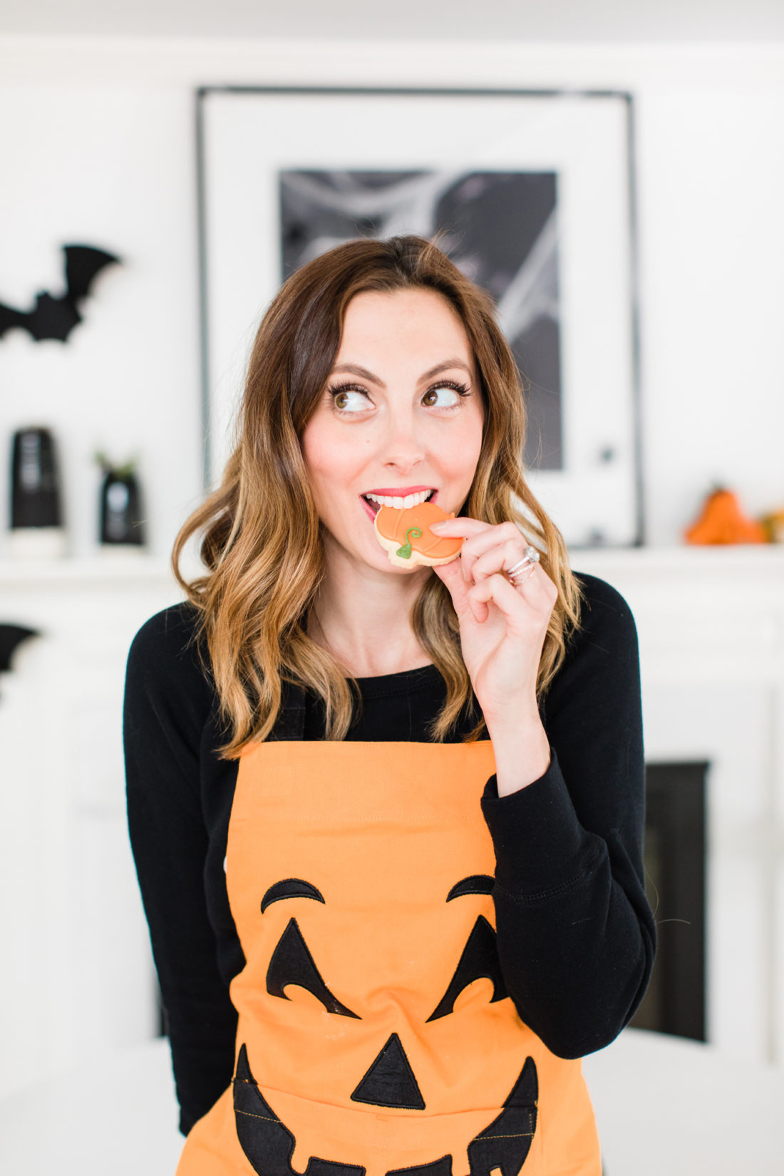 Eva Amurri Martino wears a jack-o-lantern apron and nibbles on a fall themed sugar cookie