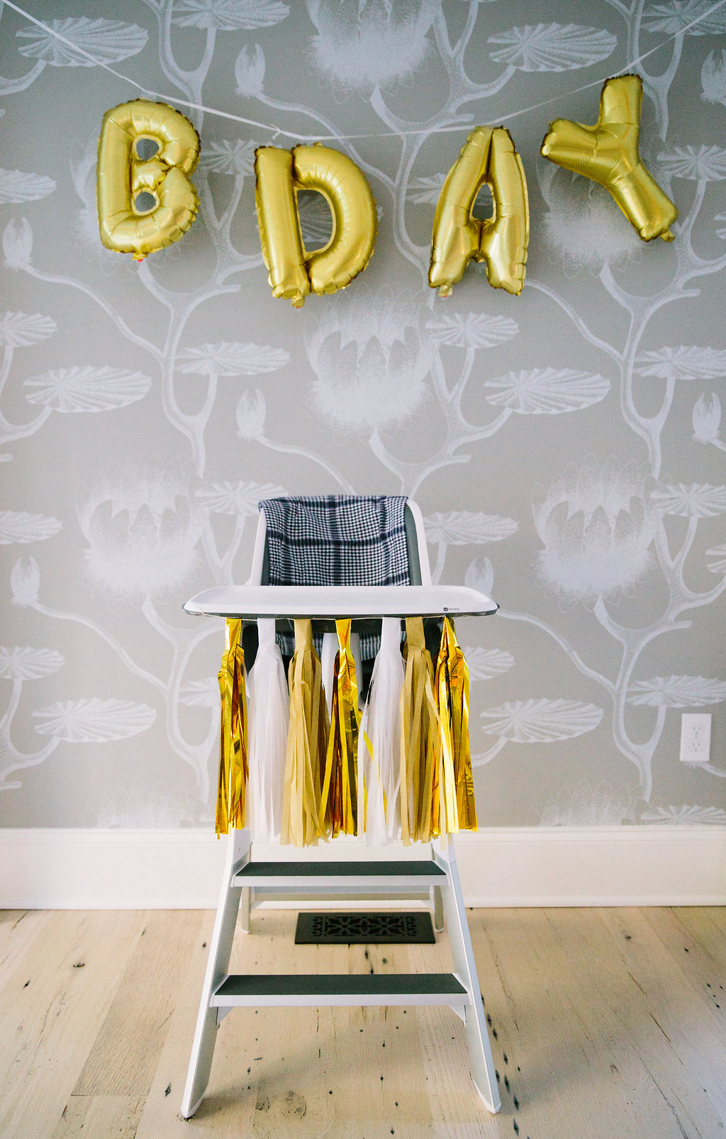 The birthday high chair set up with gold and white tassels at Major Martino's first birthday party in Connecticut