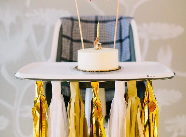 A white cake and porcelain bear on a bicycle candle holder with a home made flag bunting for Major Martino's first birthday party