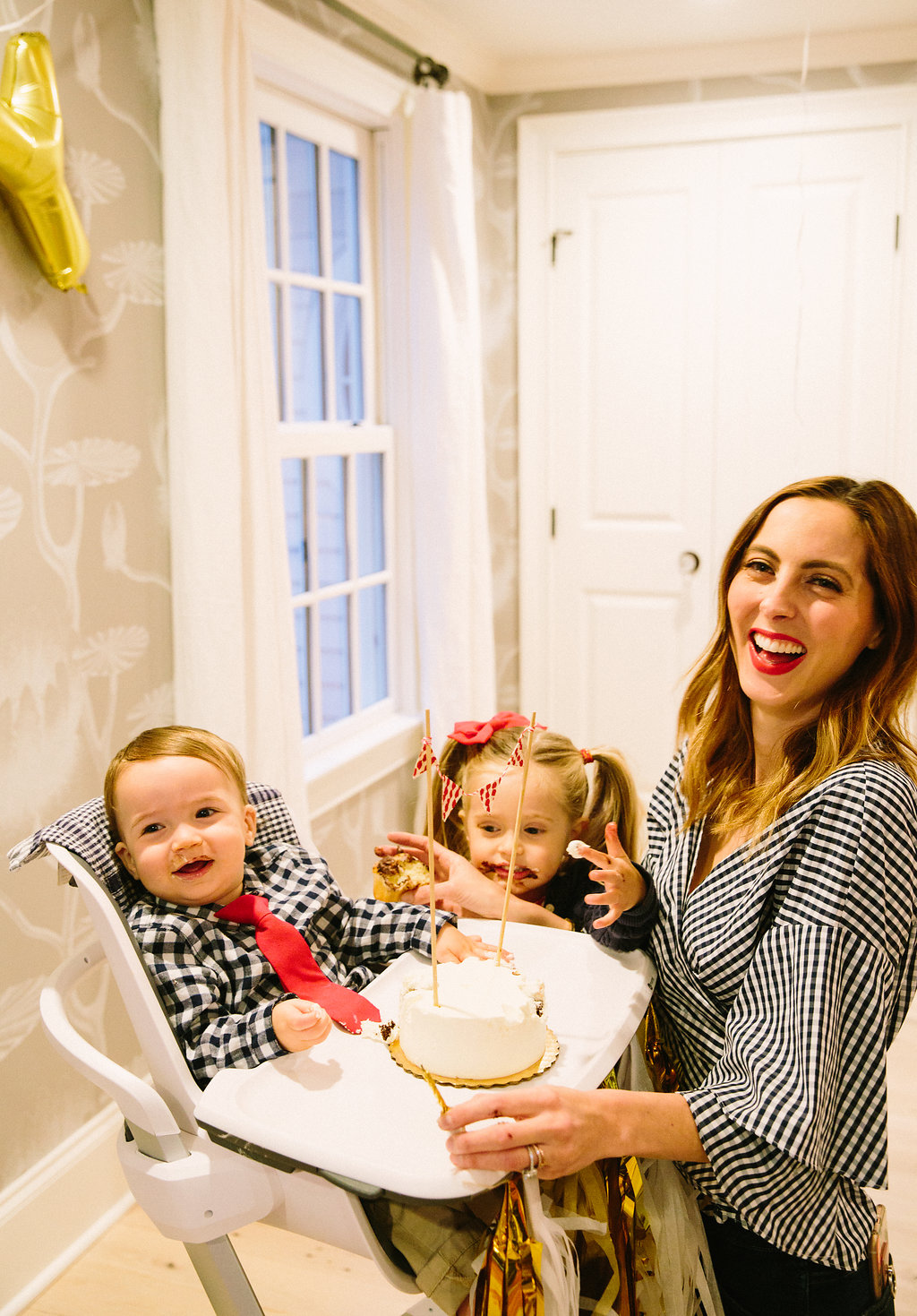 Major Martino laughs as he tries his first bites of cake on his first birthday, surrounded by sister Marlowe and Eva Martino