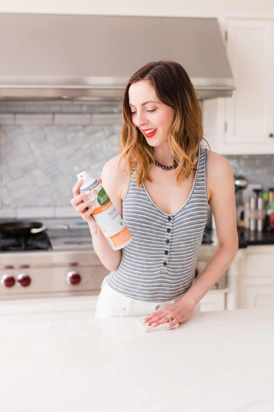Eva Amurri Martino wears a striped bodysuit and white jeans and cleans her connecticut kitchen with seventh generation spray