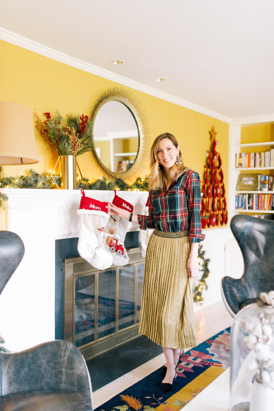 Eva Amurri Martino stands in front of the mantel in her living room that his hung with stockings for Christmas