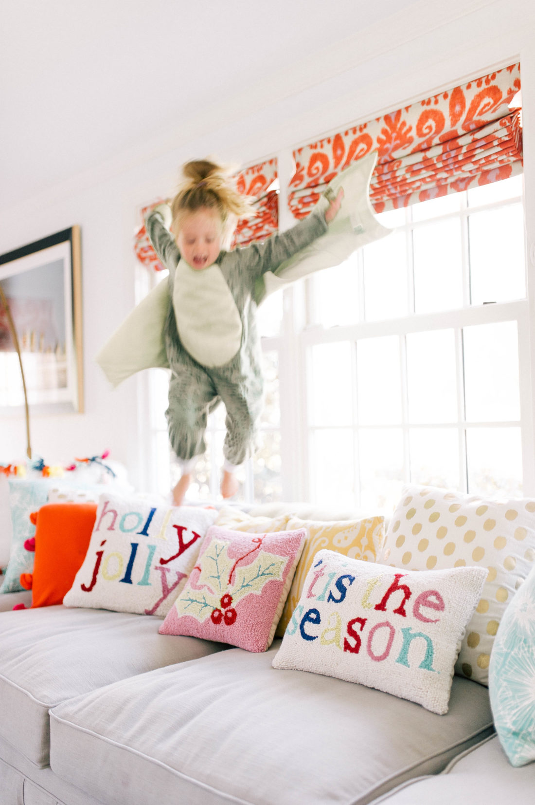 Marlowe Martino wears a green dragon costume and jumps on the colorful couch at her connecticut home