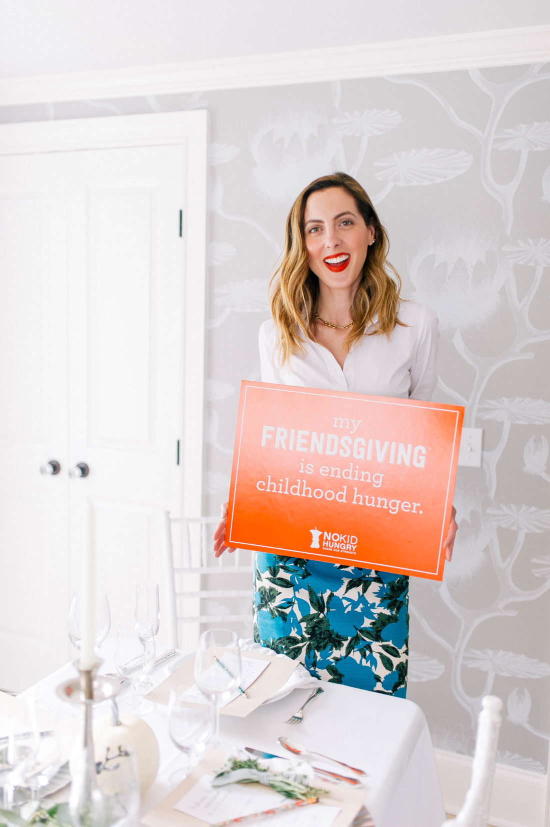 Eva Amurri Martino holds up a sign in the dining room of her connecticut home as part of her Friendsgiving event for No Kid Hungry