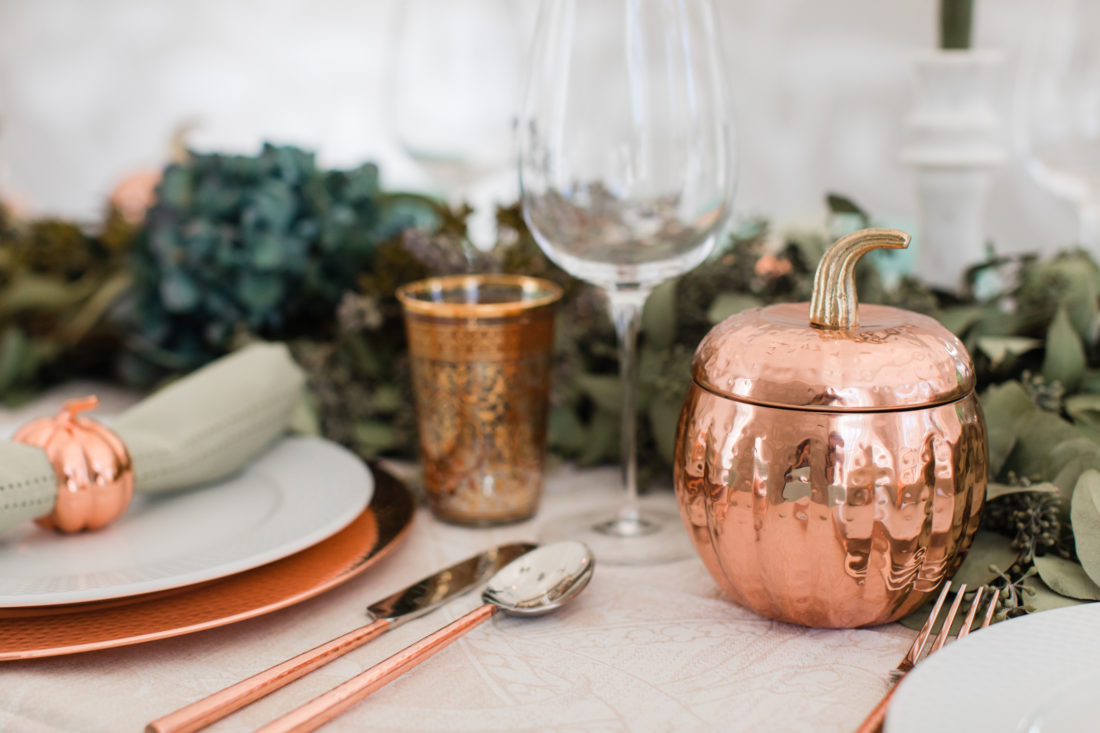 A eucaluptus garland, marble candlesticks with green candles, and a green and copper color scheme add style to Eva Amurri Martino's thanksgiving table