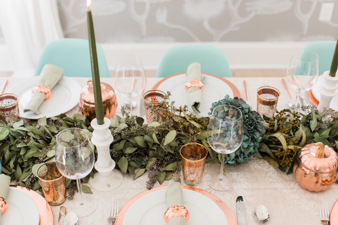 A eucaluptus garland, marble candlesticks with green candles, and a green and copper color scheme add style to Eva Amurri Martino's thanksgiving table