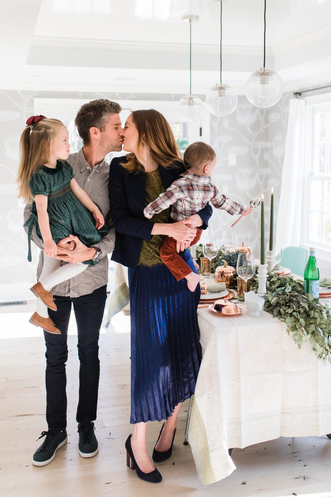 Eva Amurri martino standing with her family, Kyle Martino, Marlowe Martino, and Major Martino, in their dining room set up for Thanksgiving