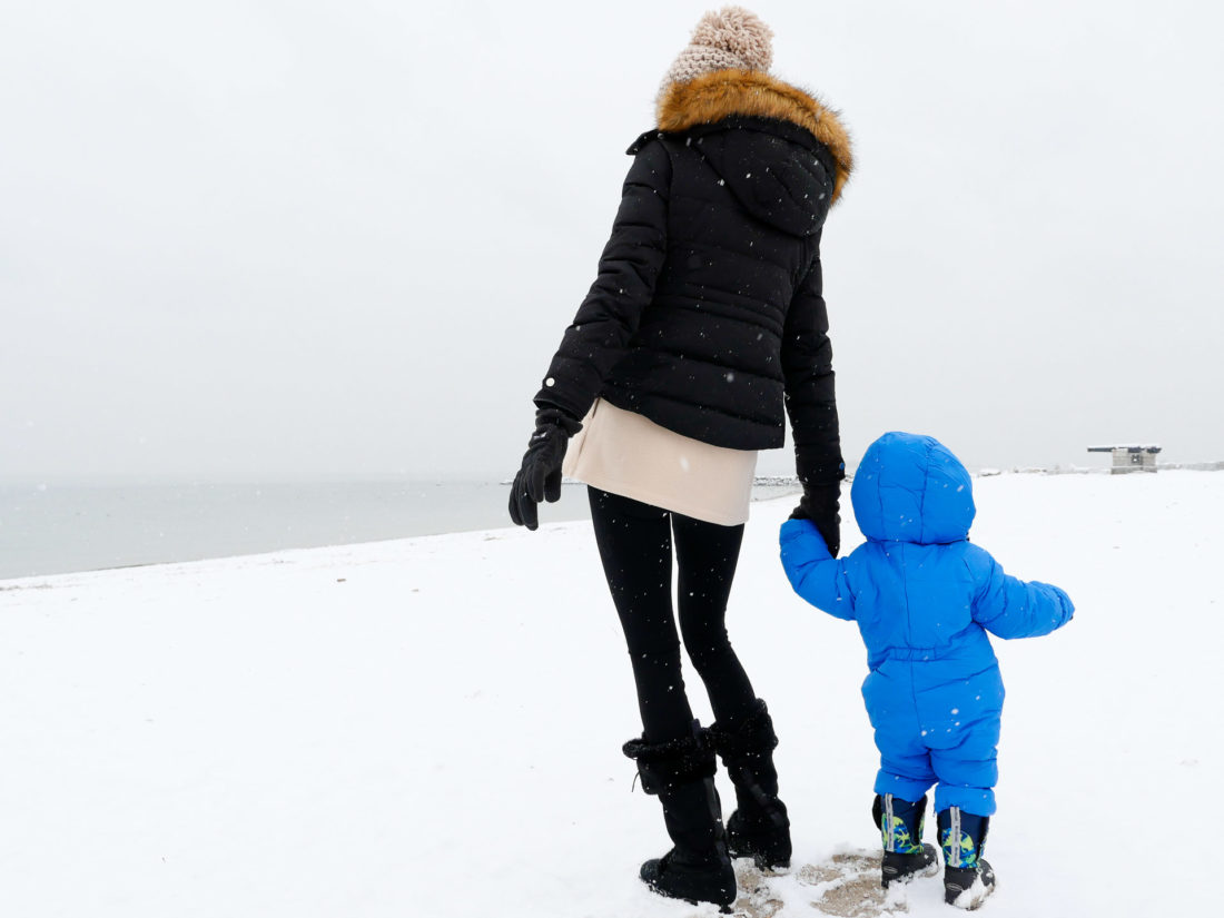 Eva Martino holds son Major's hand as they walk through the snow on the beach in Westport CT