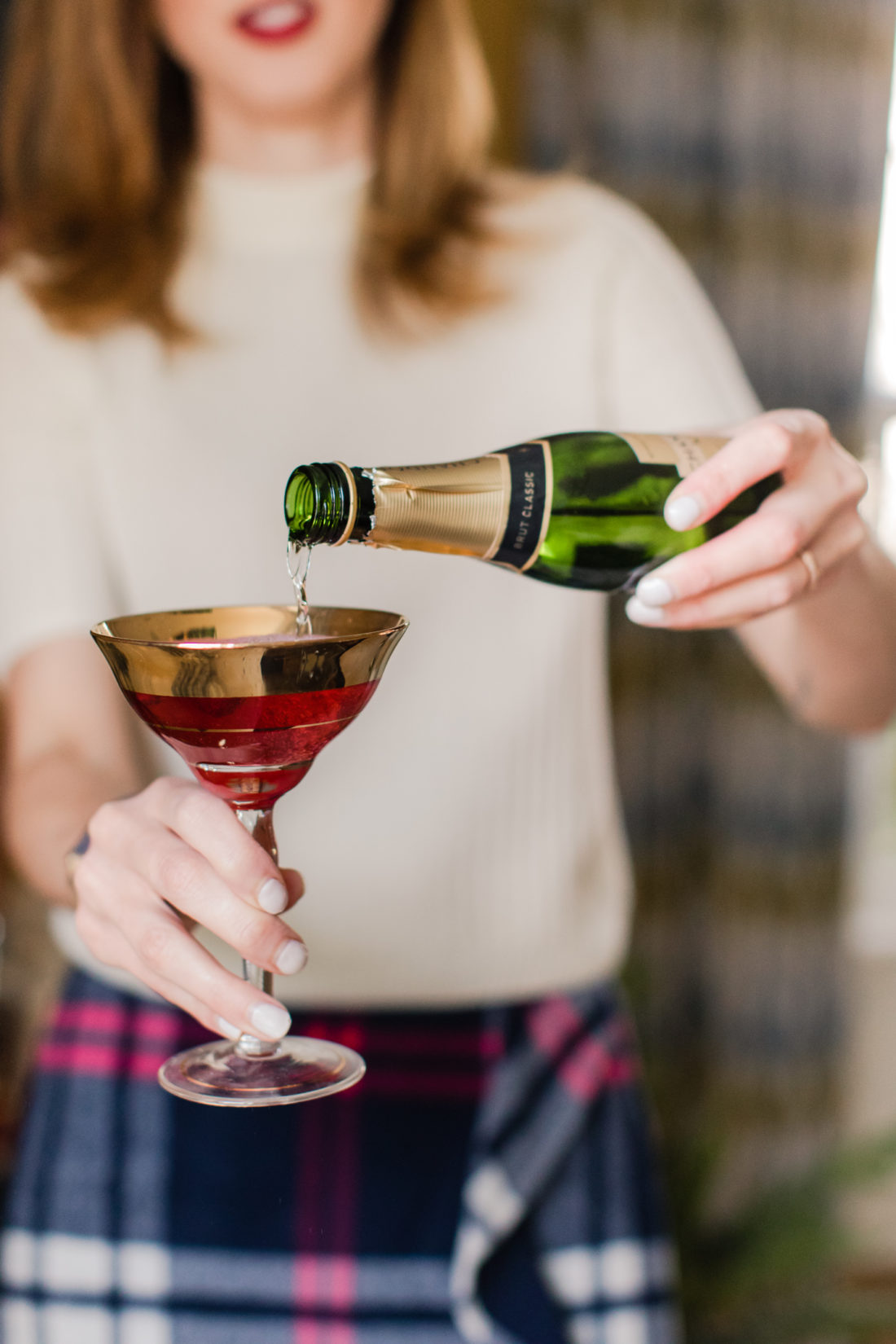 Eva Amurri Martino pours champagne in to a poinsettia cocktail in the living room of her Connecticut home