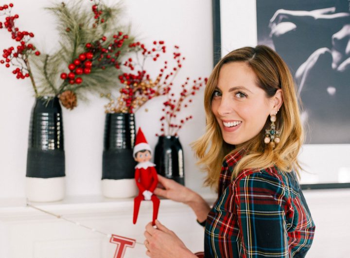 Eva Amurri Martino wears a plaid shirt and puts the Elf On The Shelf on the mantel in her kitchen