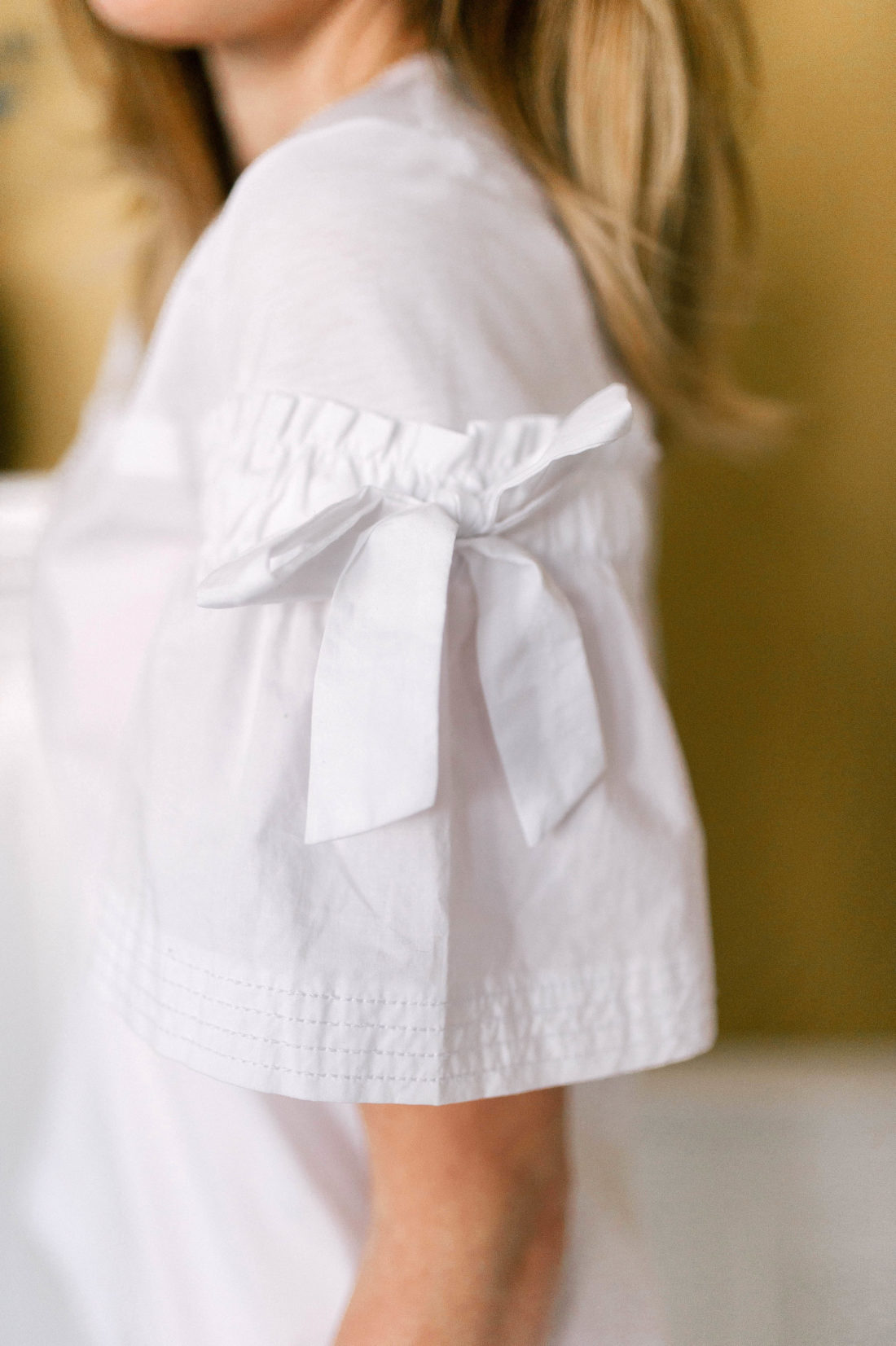 Detail of a white classic shirt with bow detail on the sleeve