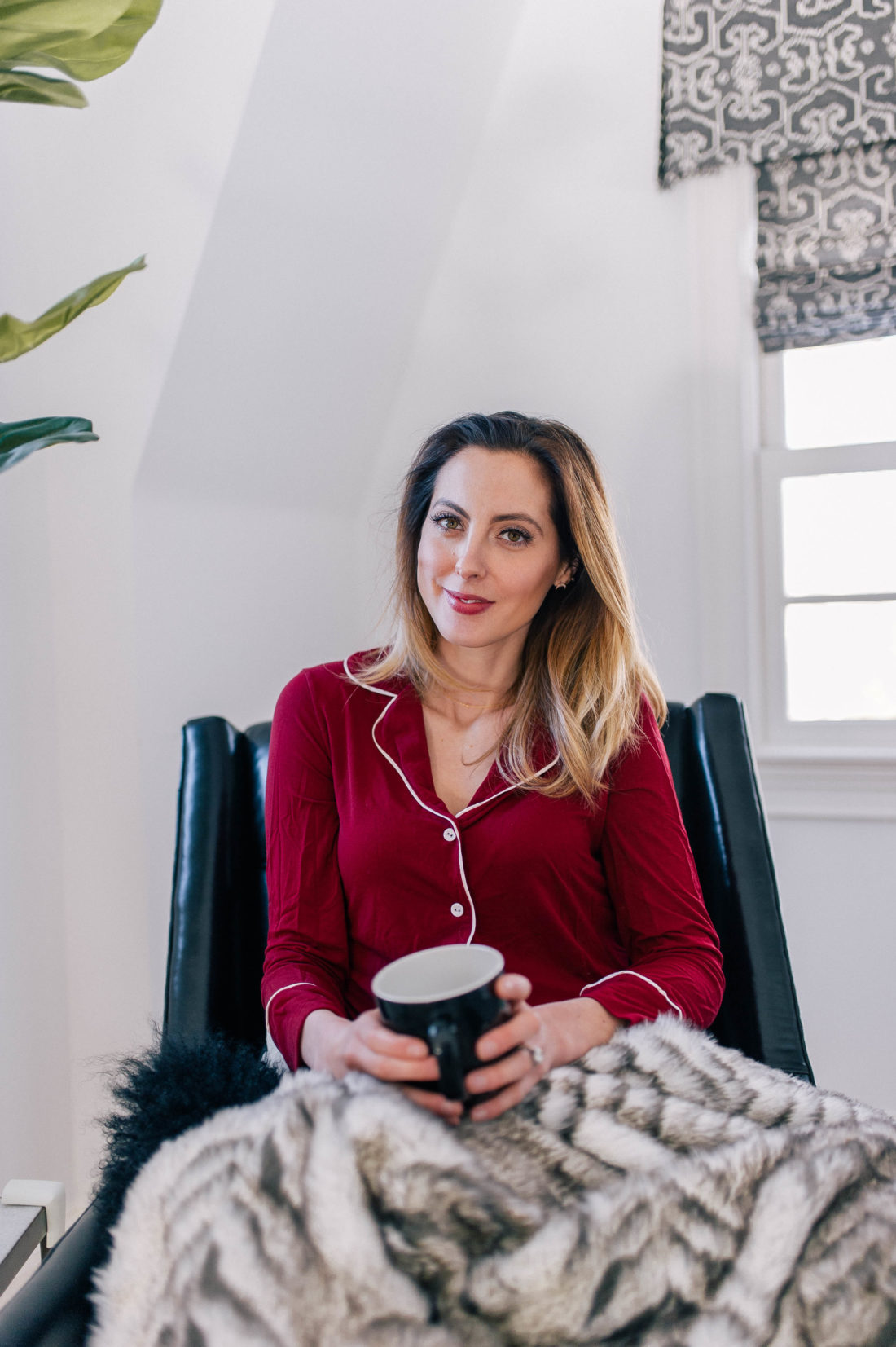 Eva Amurri Martino wears a dark red set of cozy pajamas and curls up on the leather armchair in her master bedroom with a cup of tea