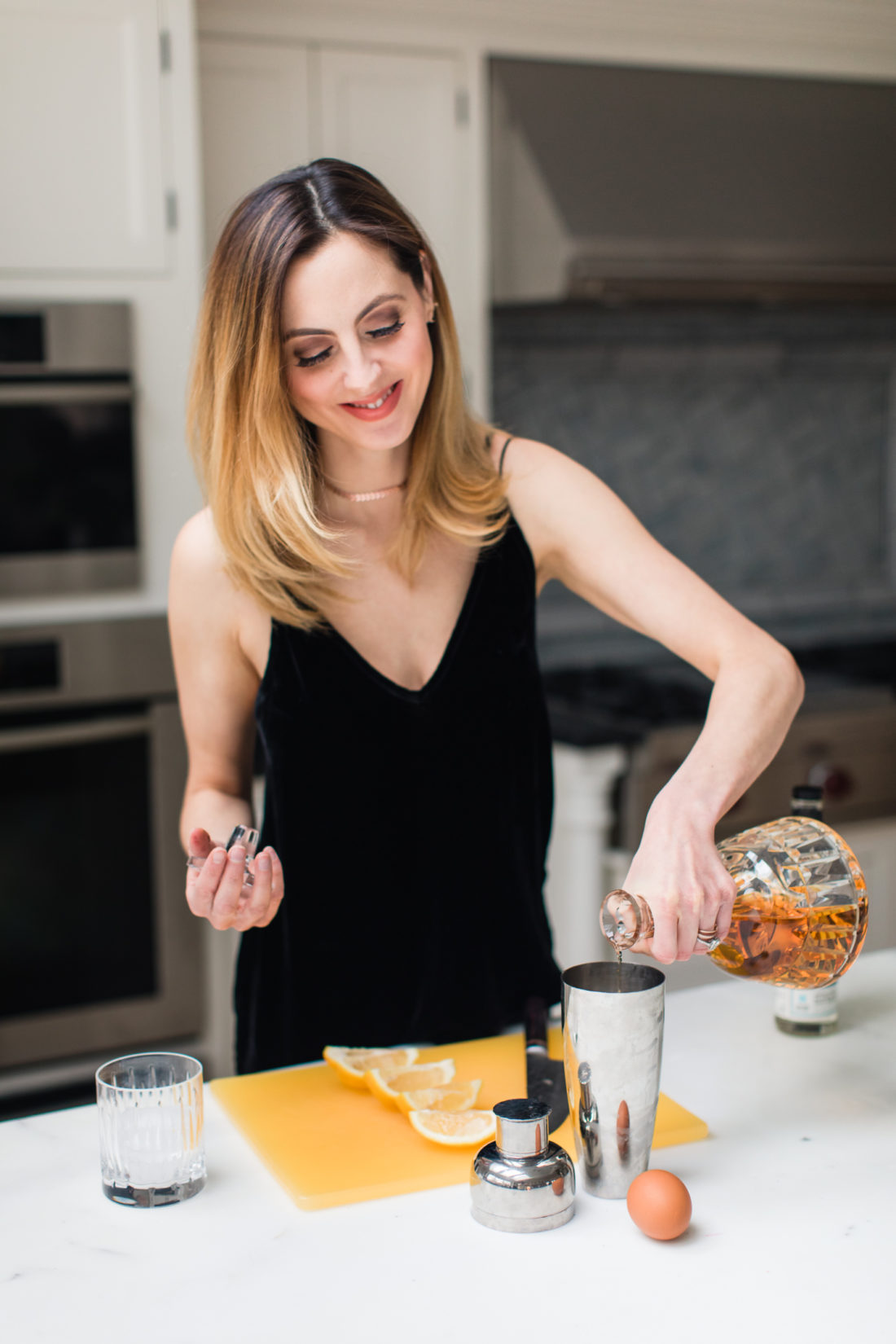 Eva Amurri Martino wears a black velvet spaghetti strap top and mixes up a whiskey sour in the kitchen of her Connecticut home