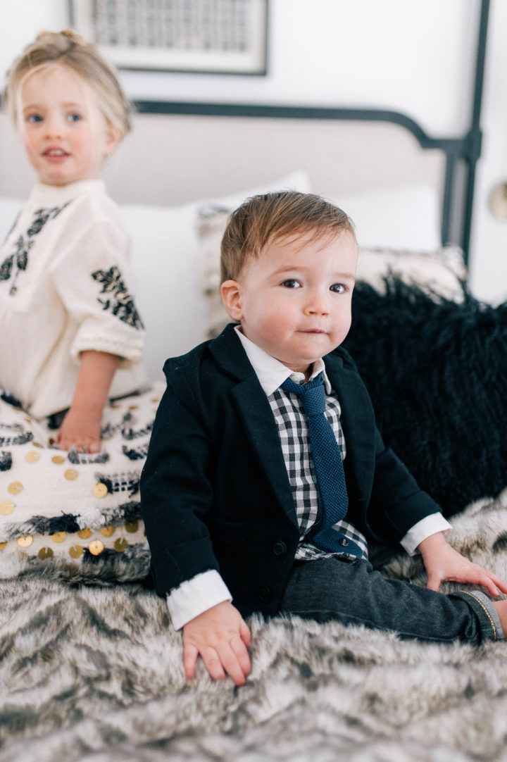 Major James Martino sits on his parents bed in a navy blue blazer and gingham shirt with his sister Marlow Mae Martino who is wearing an ivory smock dress at their house in Connecticut.