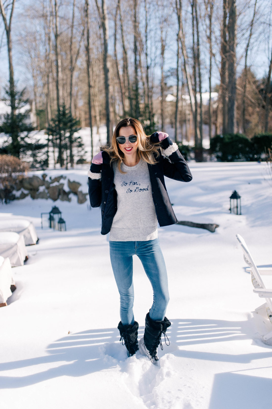 Eva Amurri Martino wears old navy jeans, black snow boots, a grey sweater and pea coat and stands in the snow outside her Connecticut home