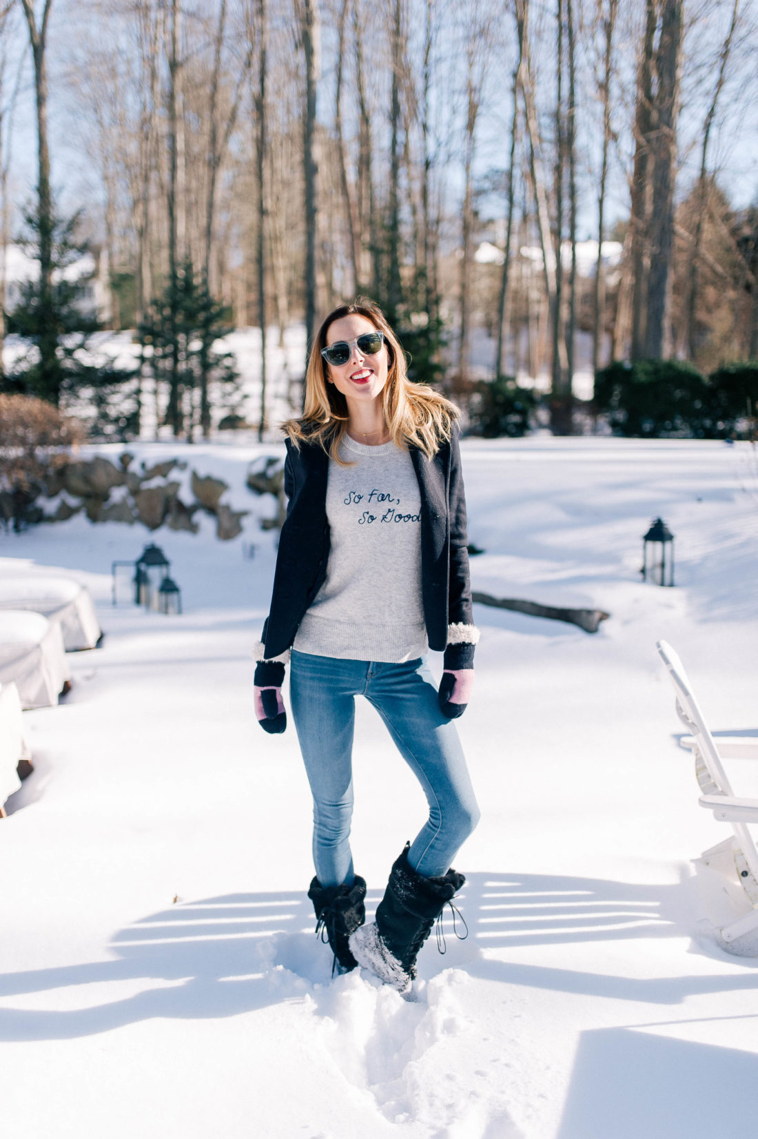 Eva Amurri Martino wears old navy jeans, black snow boots, a grey sweater and pea coat and stands in the snow outside her Connecticut home