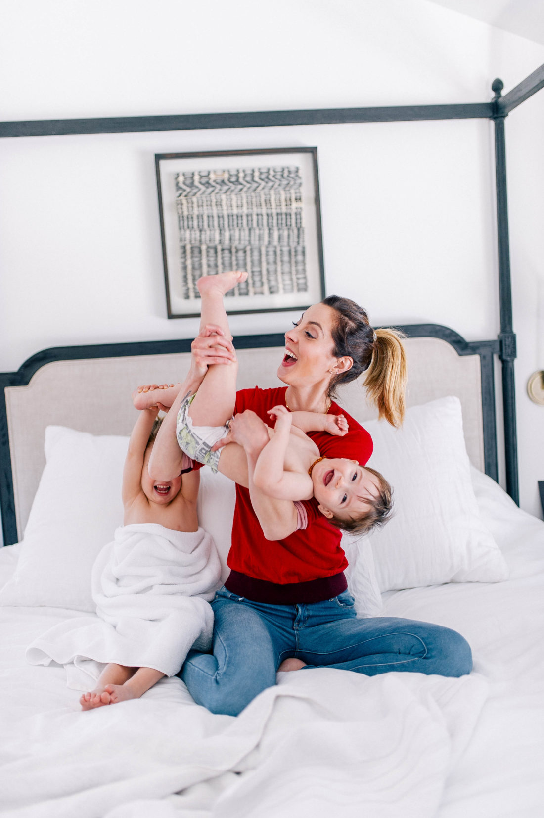 Eva Amurri Martino wears a red sweater and jeans, and lifts one year old son, Major, in the air to tickle him