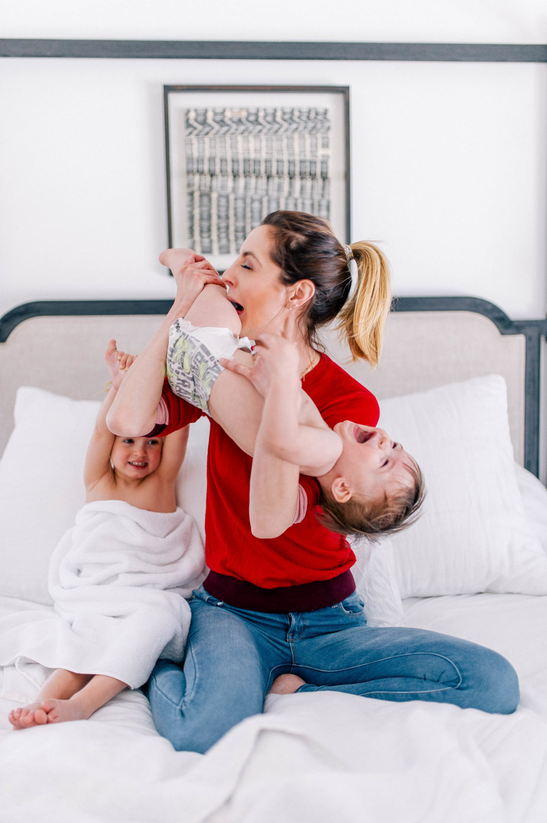 Eva Amurri Martino wears a red sweater and jeans, and lifts one year old son, Major, in the air to tickle him