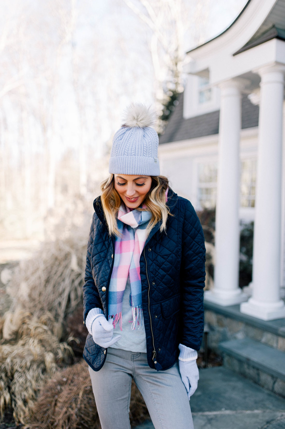 Eva Amurri Martino wears a navy quilted jacket, pastel plaid scarf and a pompom hat in the garden of her Connecticut home