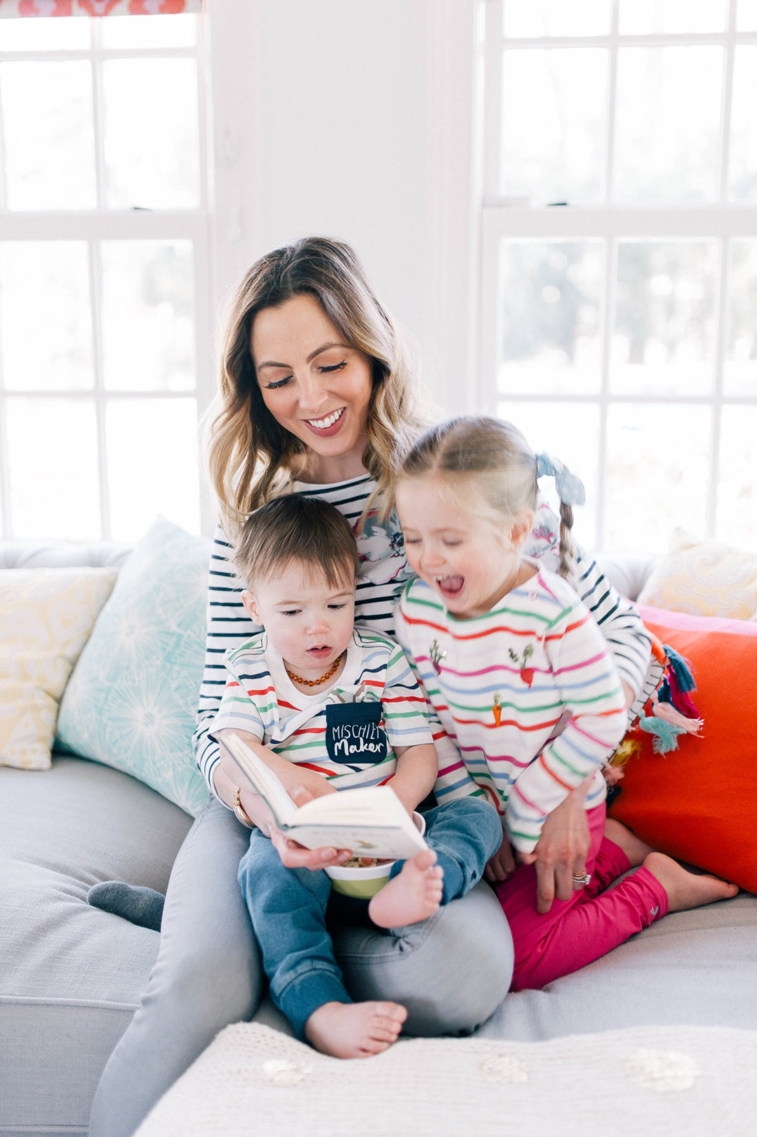 Eva Amurri Martino wears stripes and reads the Peter RAbbit book to her children on the couch at home in Connecticut