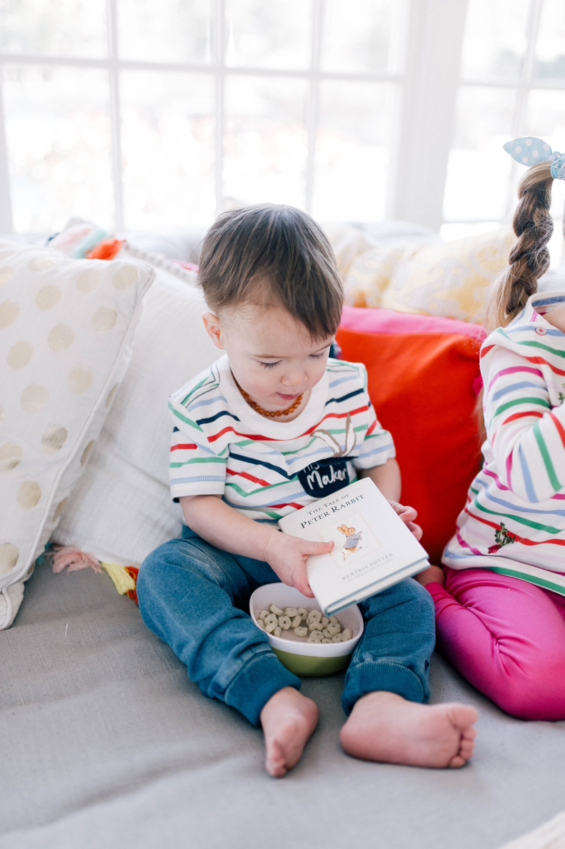 Major Martino wears a striped top and reads Peter Rabbit with a bowl of snacks