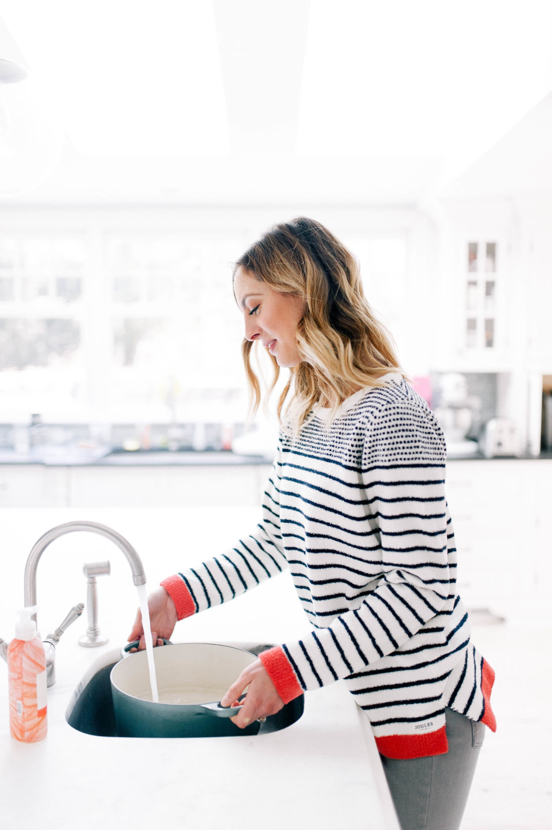 Eva Amurri Martino wears a cozy striped sweater and fills up a pot of water at the kitchen sink