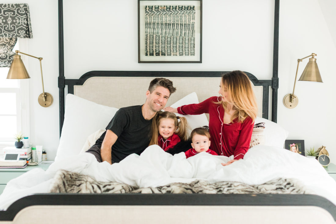 Eva Amurri martino, Kyle Martino, and children Marlowe and Major Martino cuddle in bed wearing red pajamas for Valentine's Day in the master bedroom of their Connecticut home